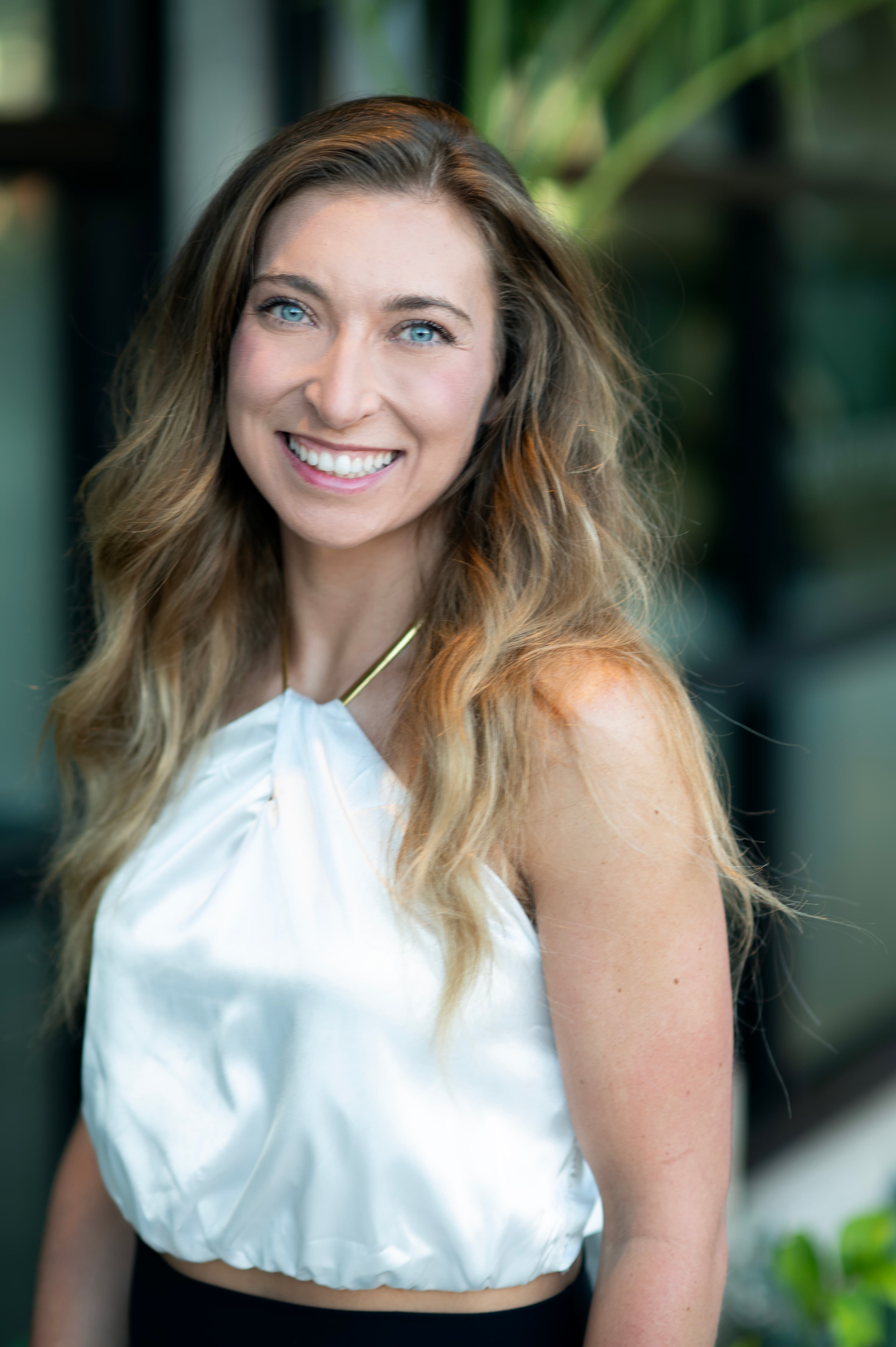 Sarah Farrell smiling in a natural light headshot wearing a white top